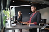 a woman standing at a desk using a computer