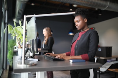 a woman standing at a desk using a computer