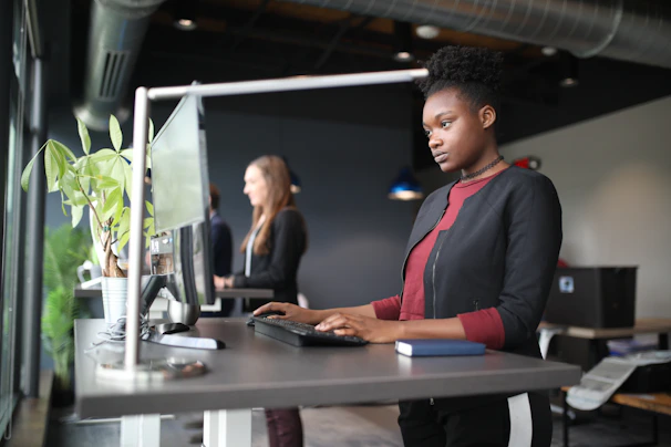 a woman standing at a desk using a computer