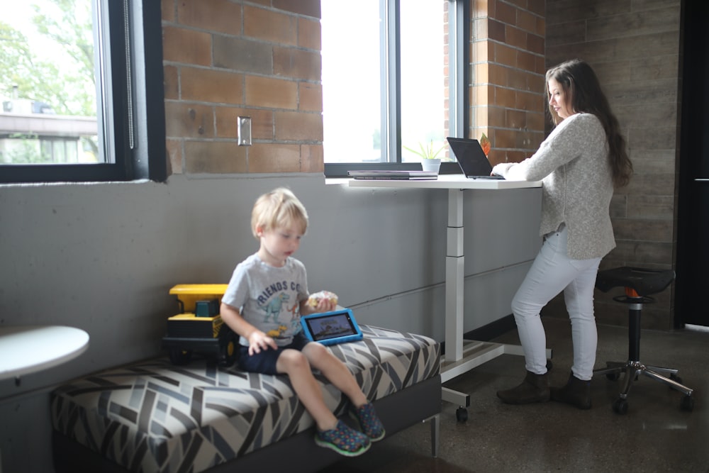 a woman standing next to a child on a bed