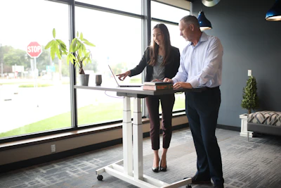 a man and a woman standing at a desk in front of a window