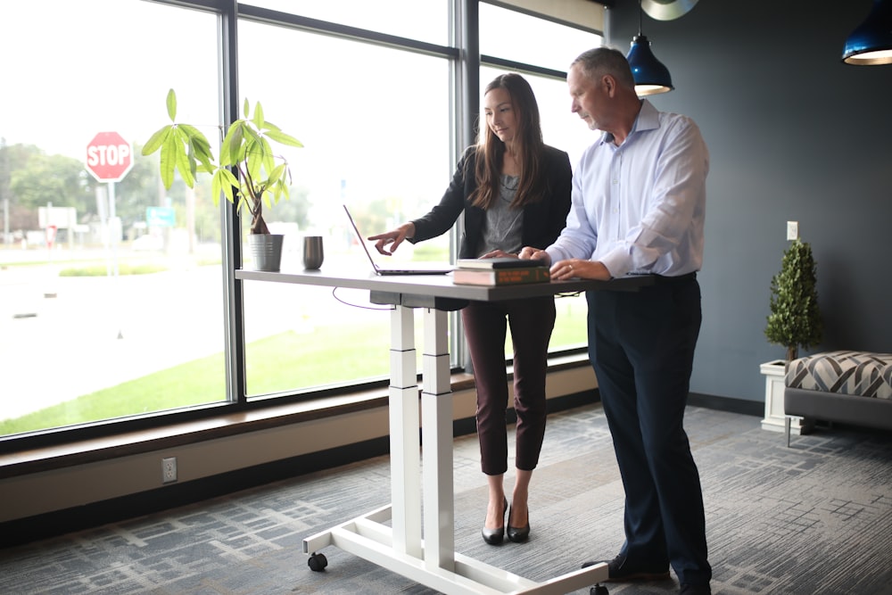 a man and a woman standing at a desk in front of a window