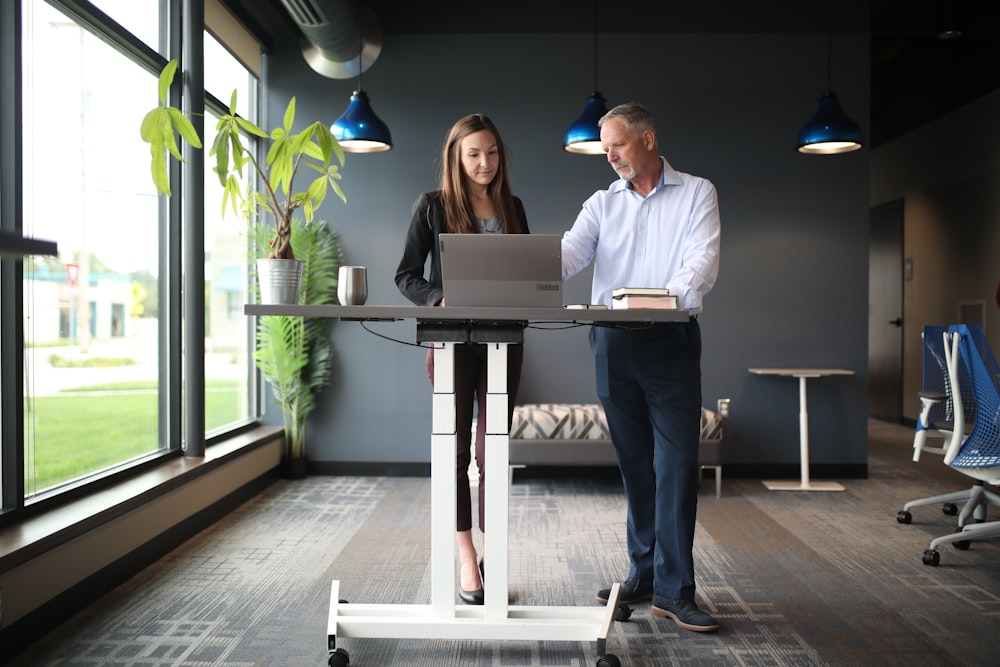 a man and a woman standing in front of a laptop computer