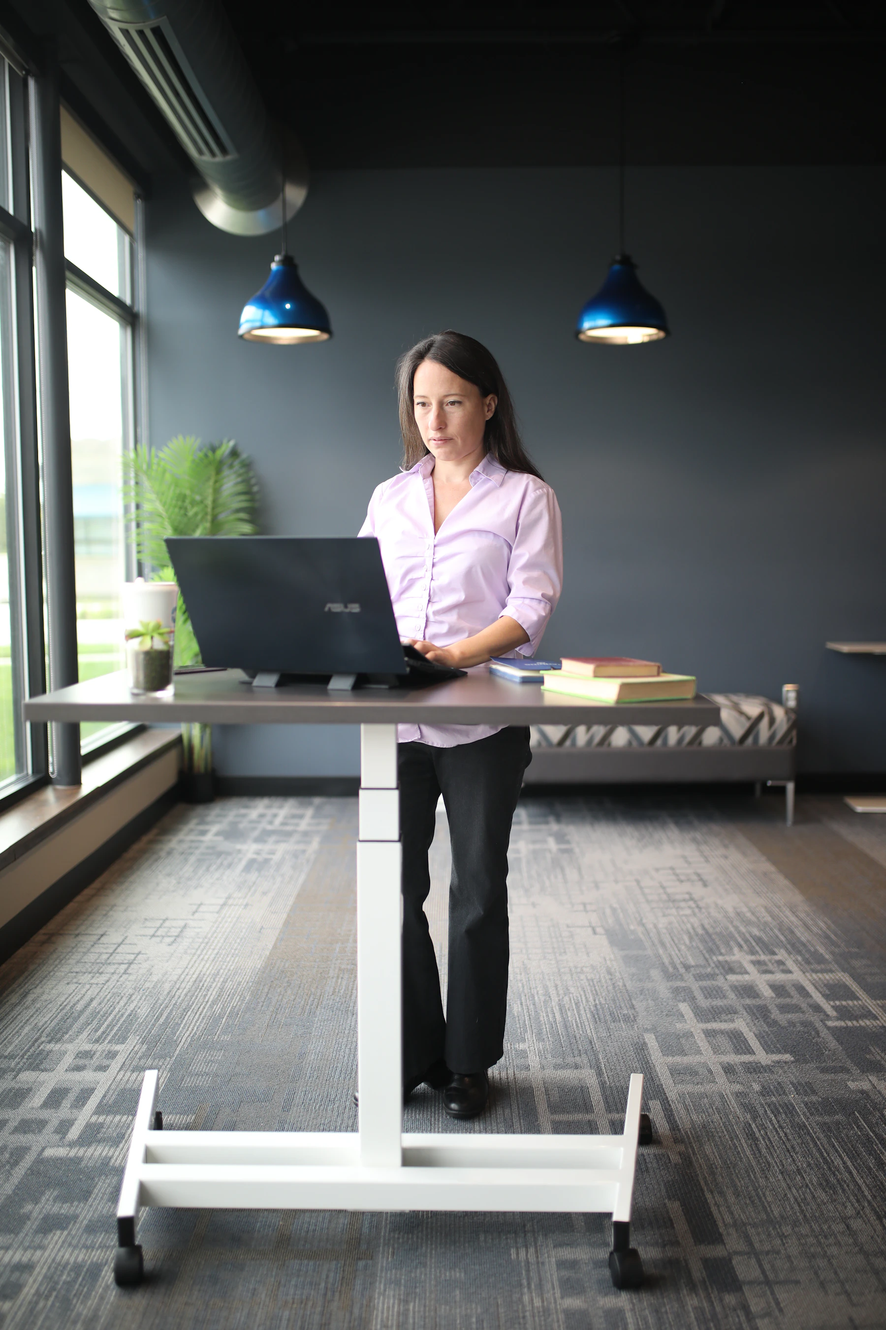 Professional working at a standing desk with a laptop in a bright office