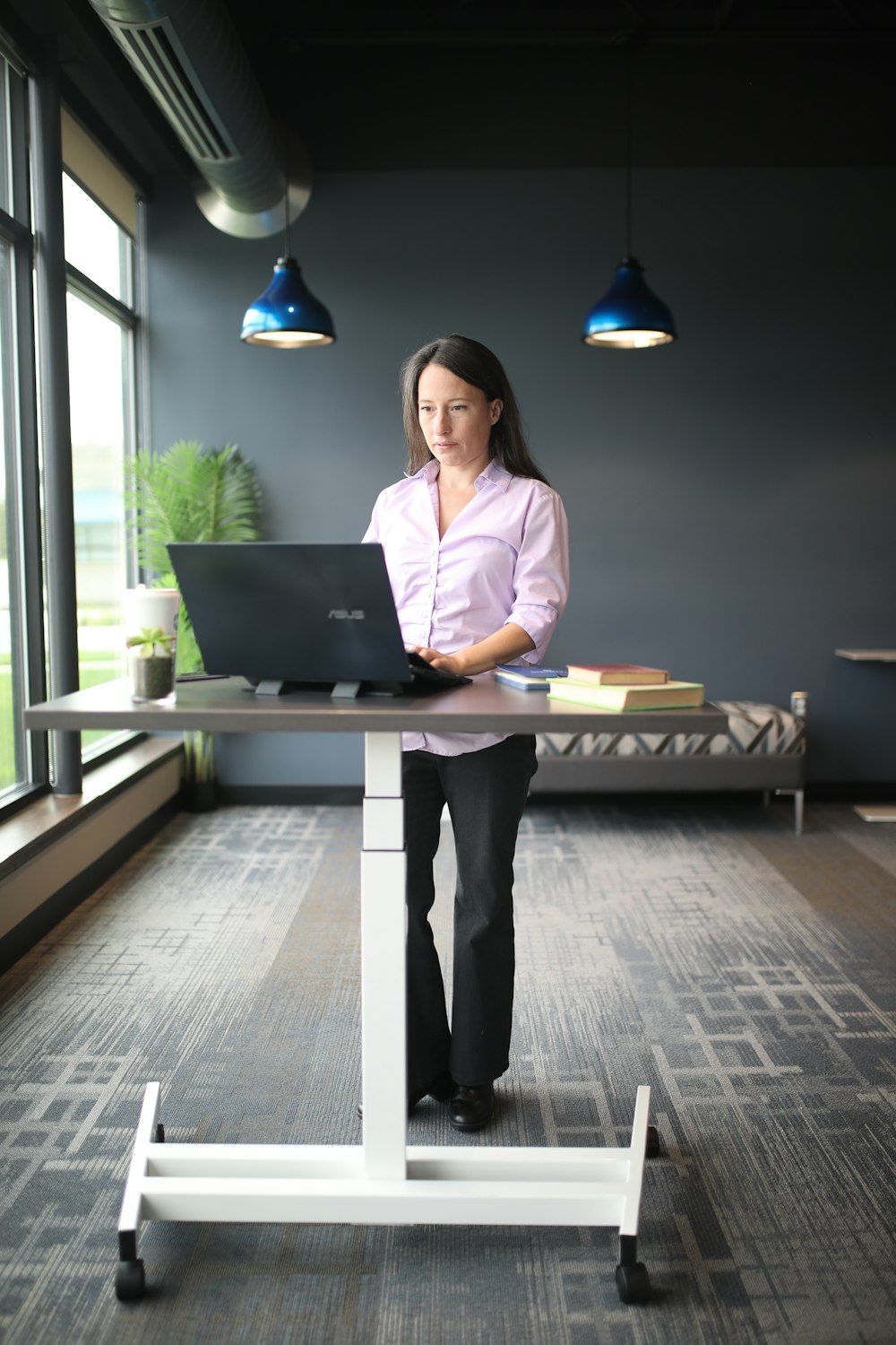 a woman standing at a desk with a laptop