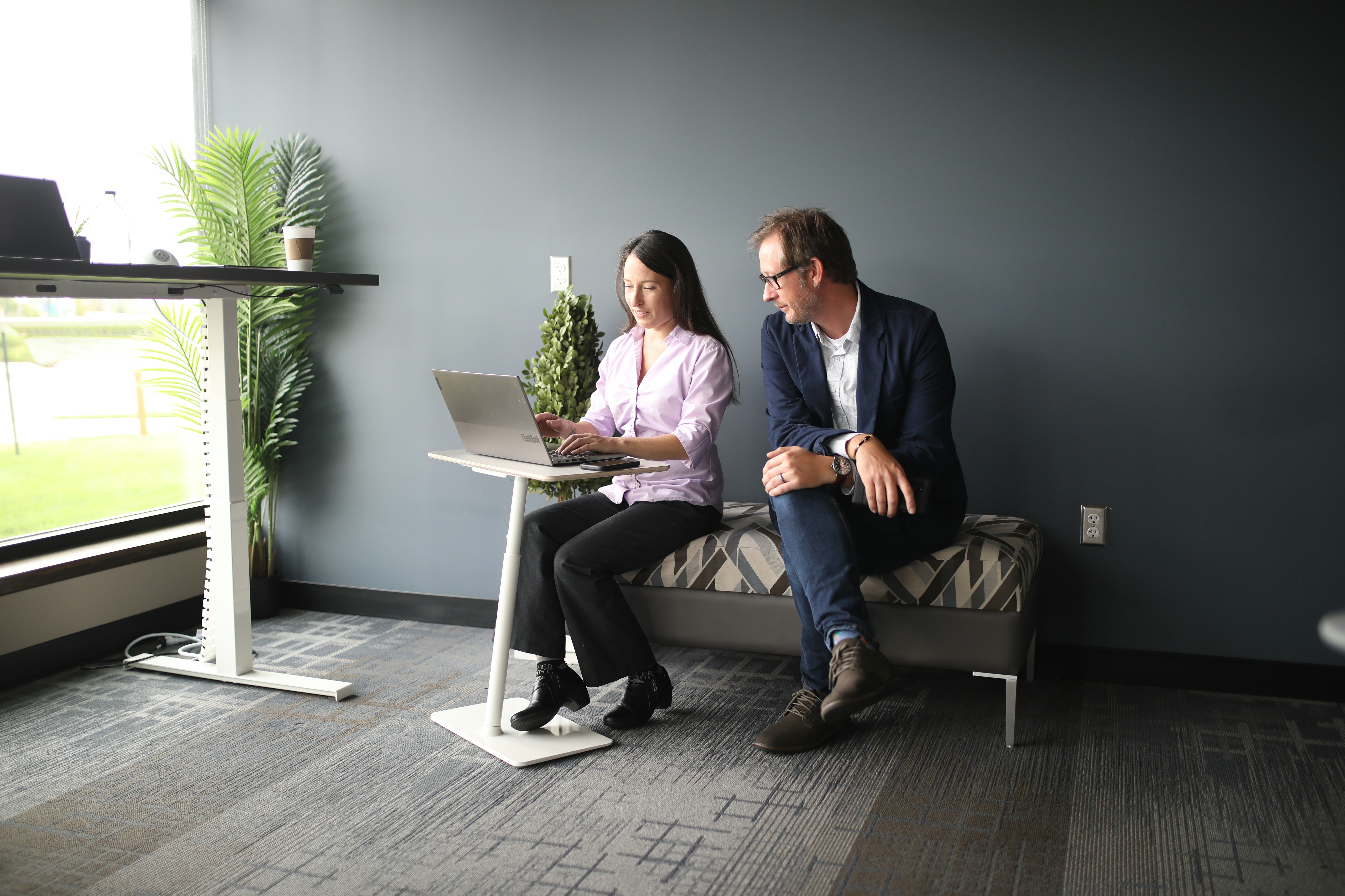 A couple looking at a tablet displaying apartment floor plans in a modern leasing office. - high rise apartments near me