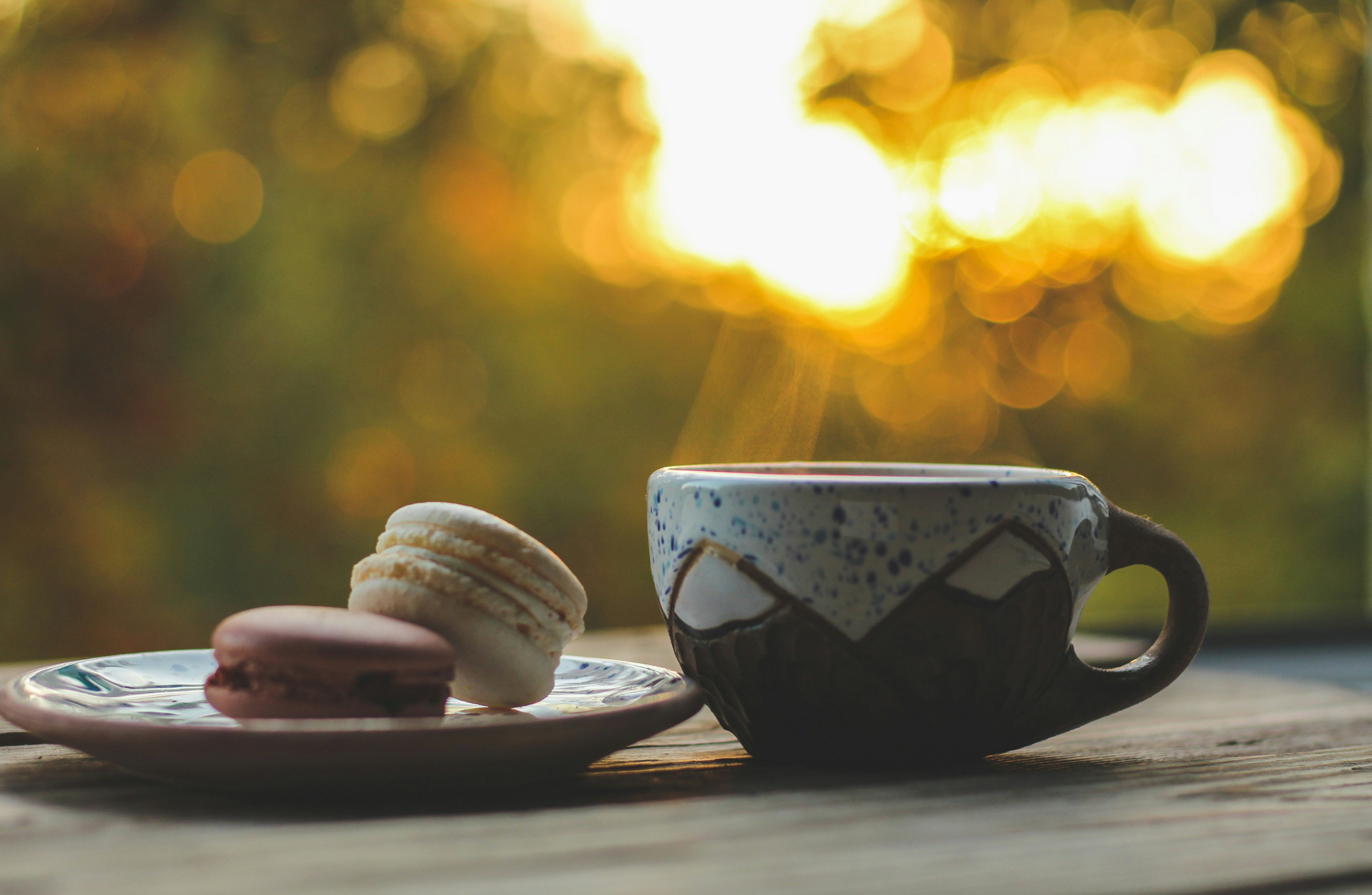 a cup of coffee next to a plate of cookies