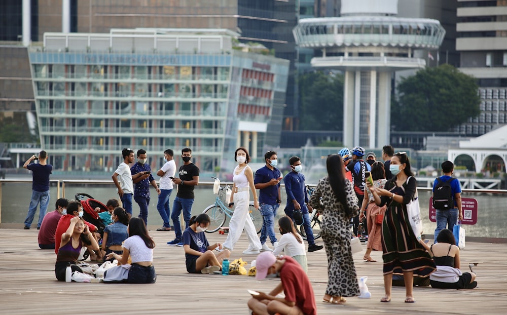 a group of people standing and sitting on top of a pier