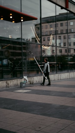 a person holding a large metal pole in front of a building