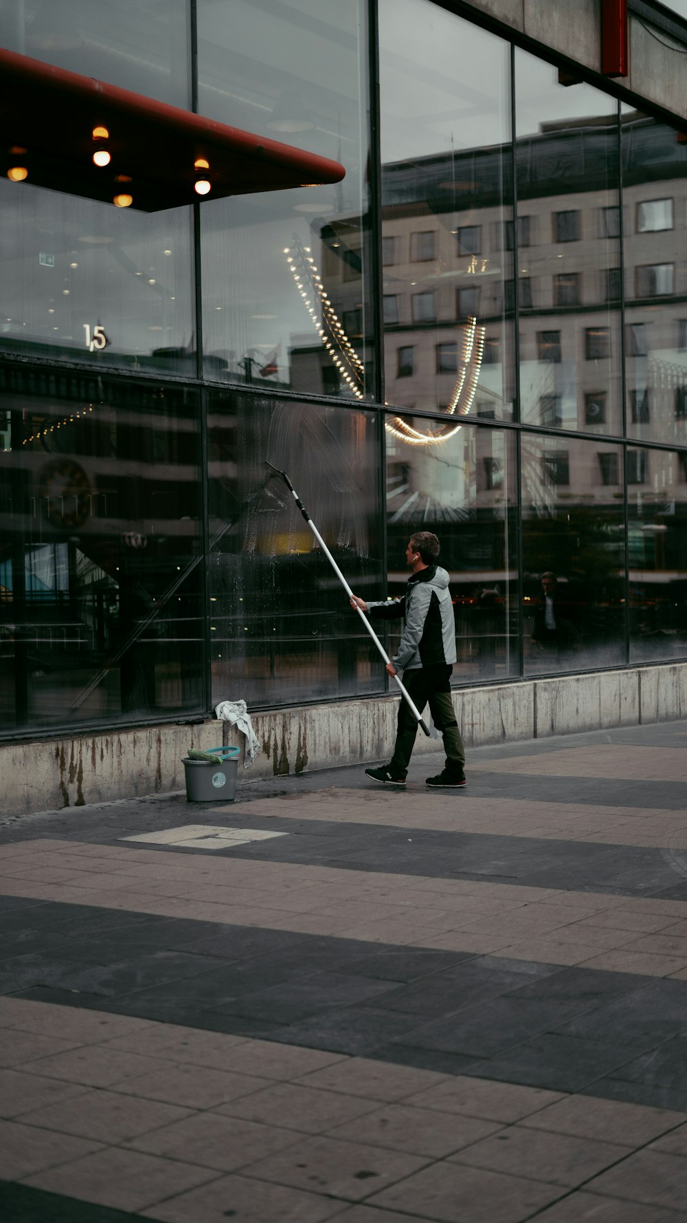 a person holding a large metal pole in front of a building