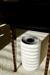 a white air conditioner sitting under a table