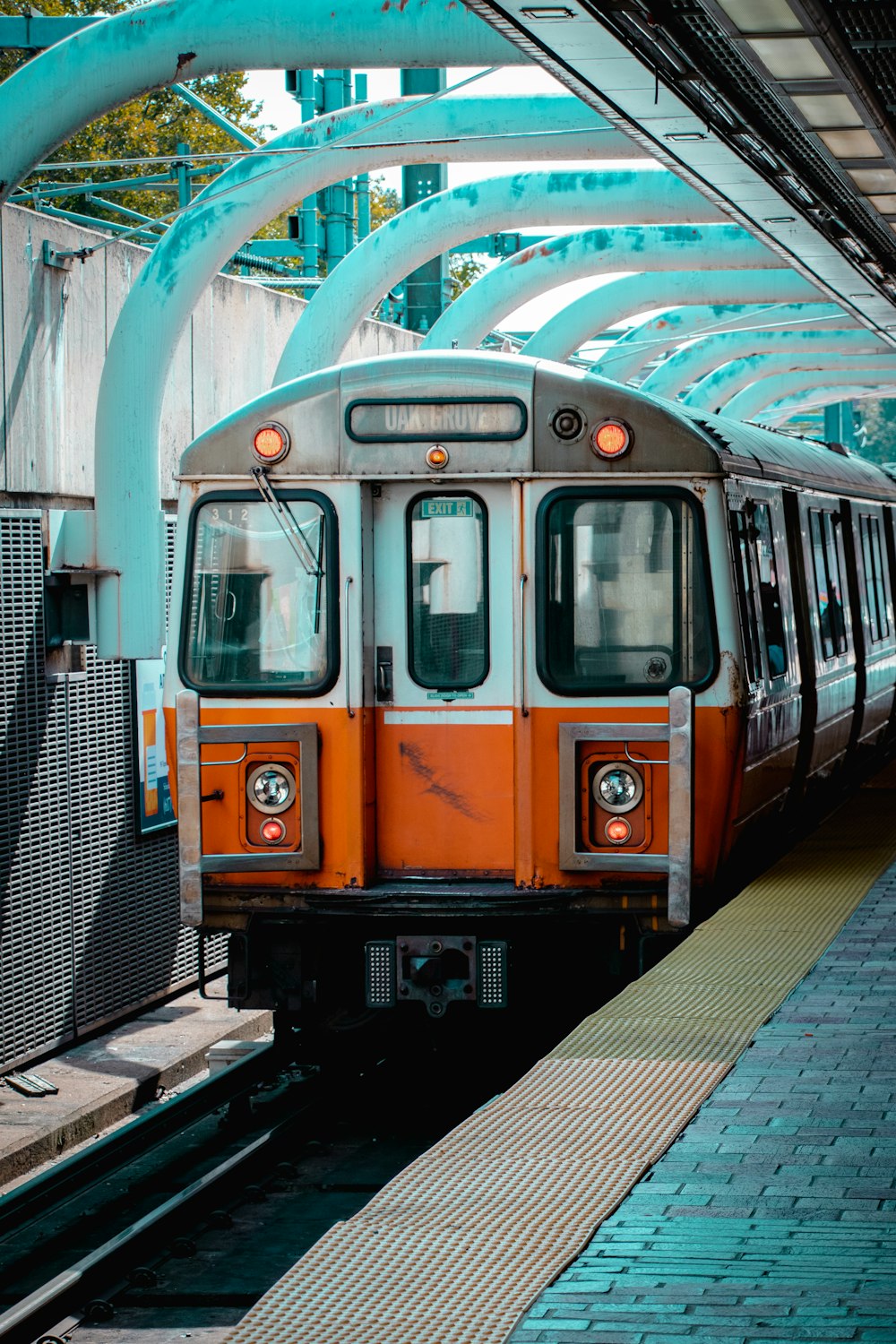 an orange and white train pulling into a train station