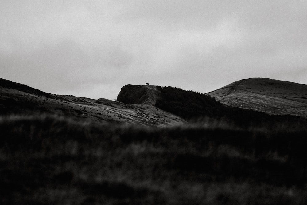 a black and white photo of a person standing on top of a hill