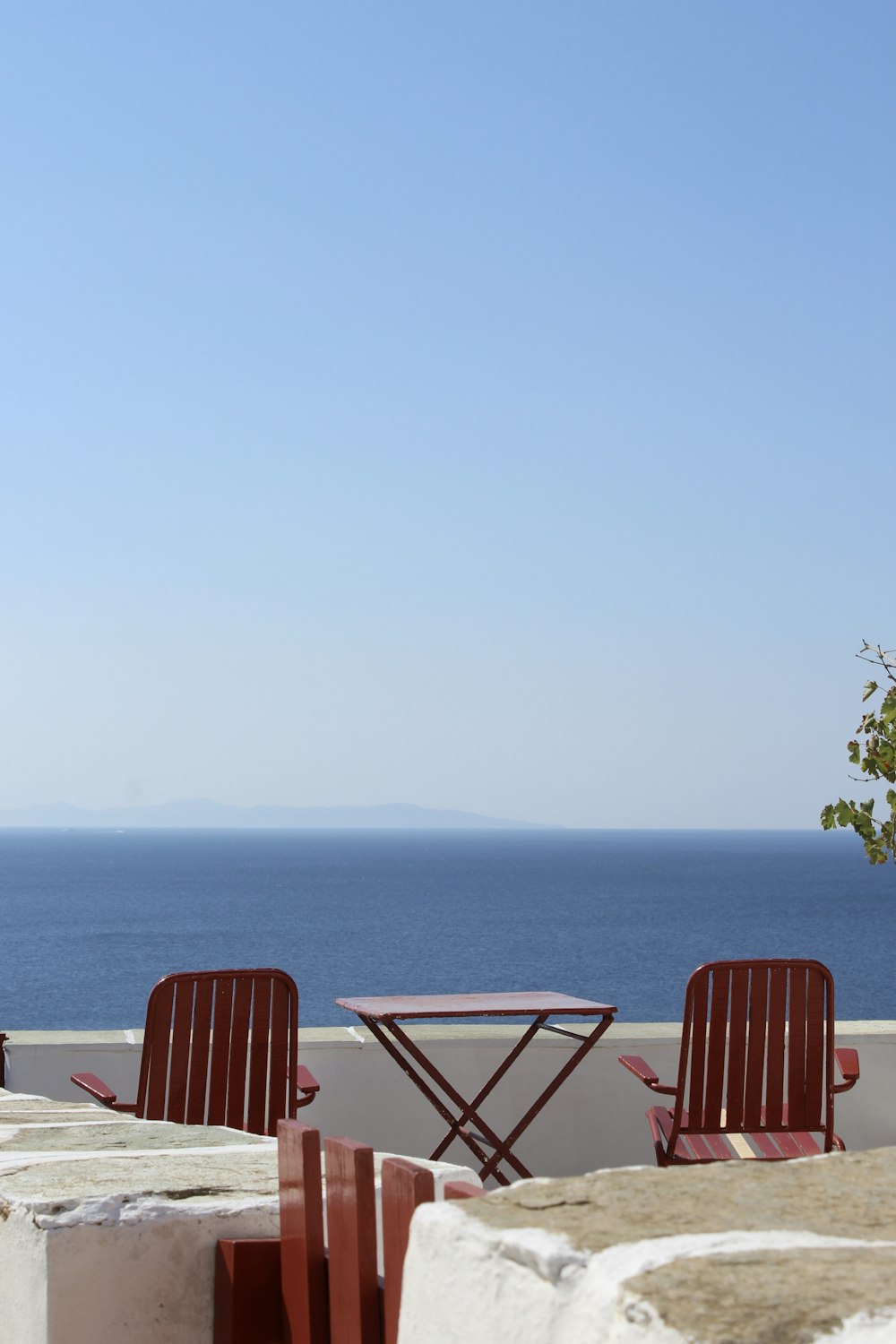 two chairs and a table on a balcony overlooking the ocean