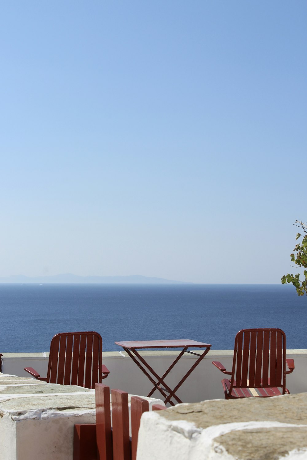 Zwei Stühle und ein Tisch auf einem Balkon mit Blick auf den Ozean