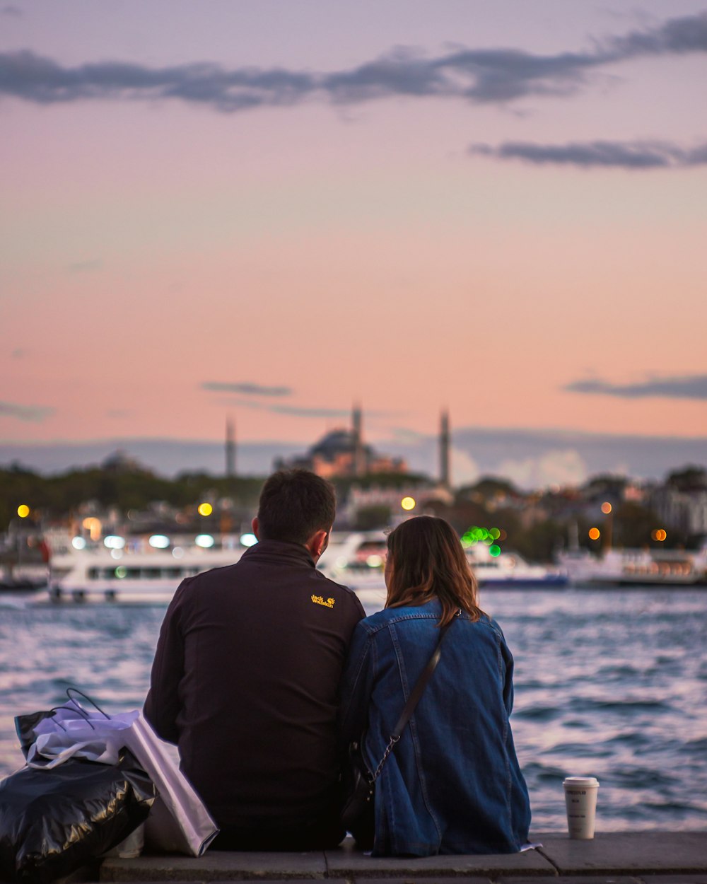 a man and a woman sitting on a dock looking at the water