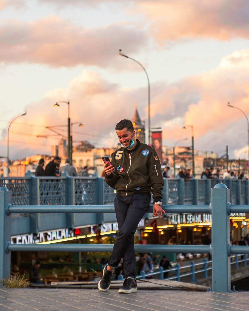 a man standing on a bridge looking at his cell phone