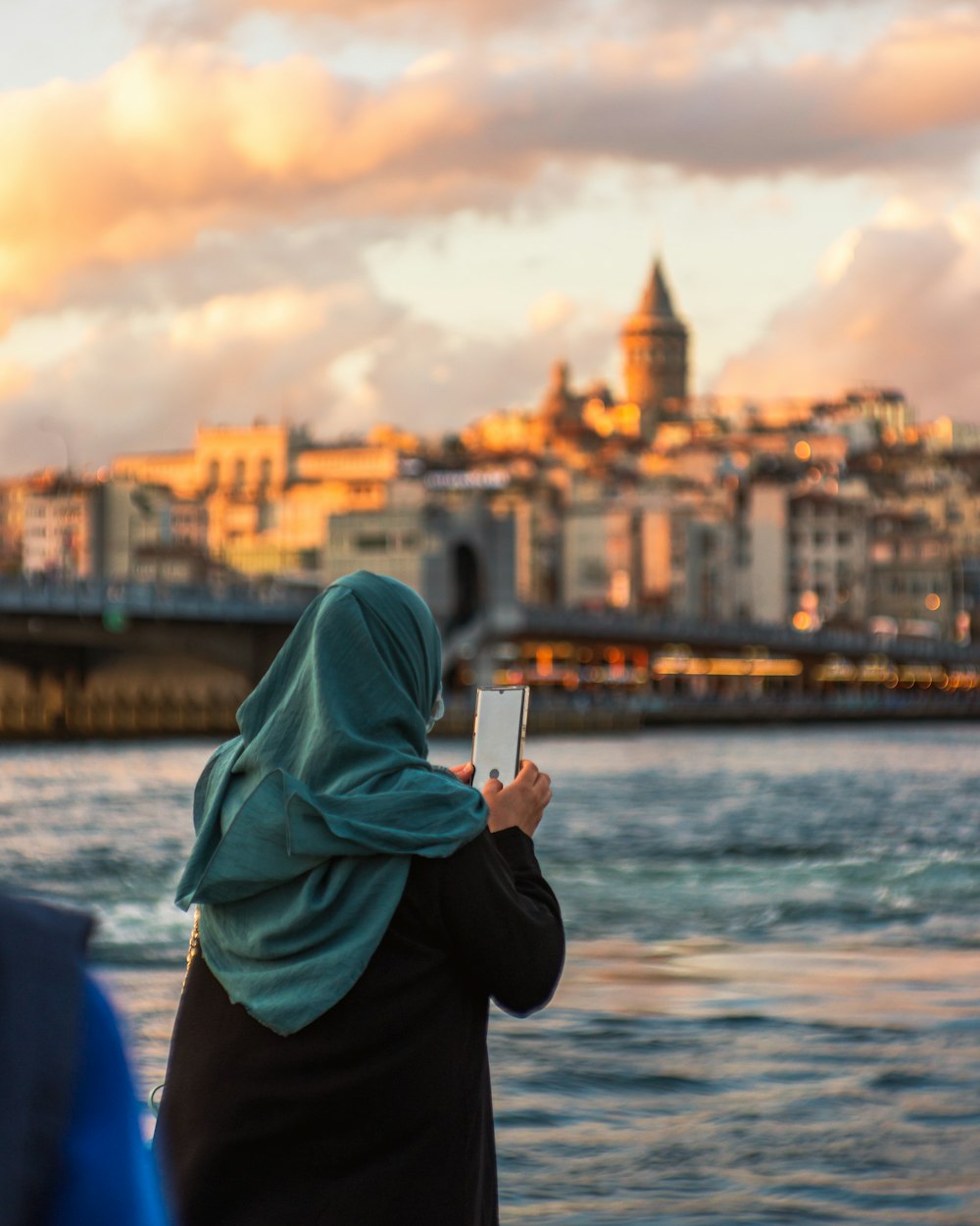 a woman in a headscarf taking a picture of a city