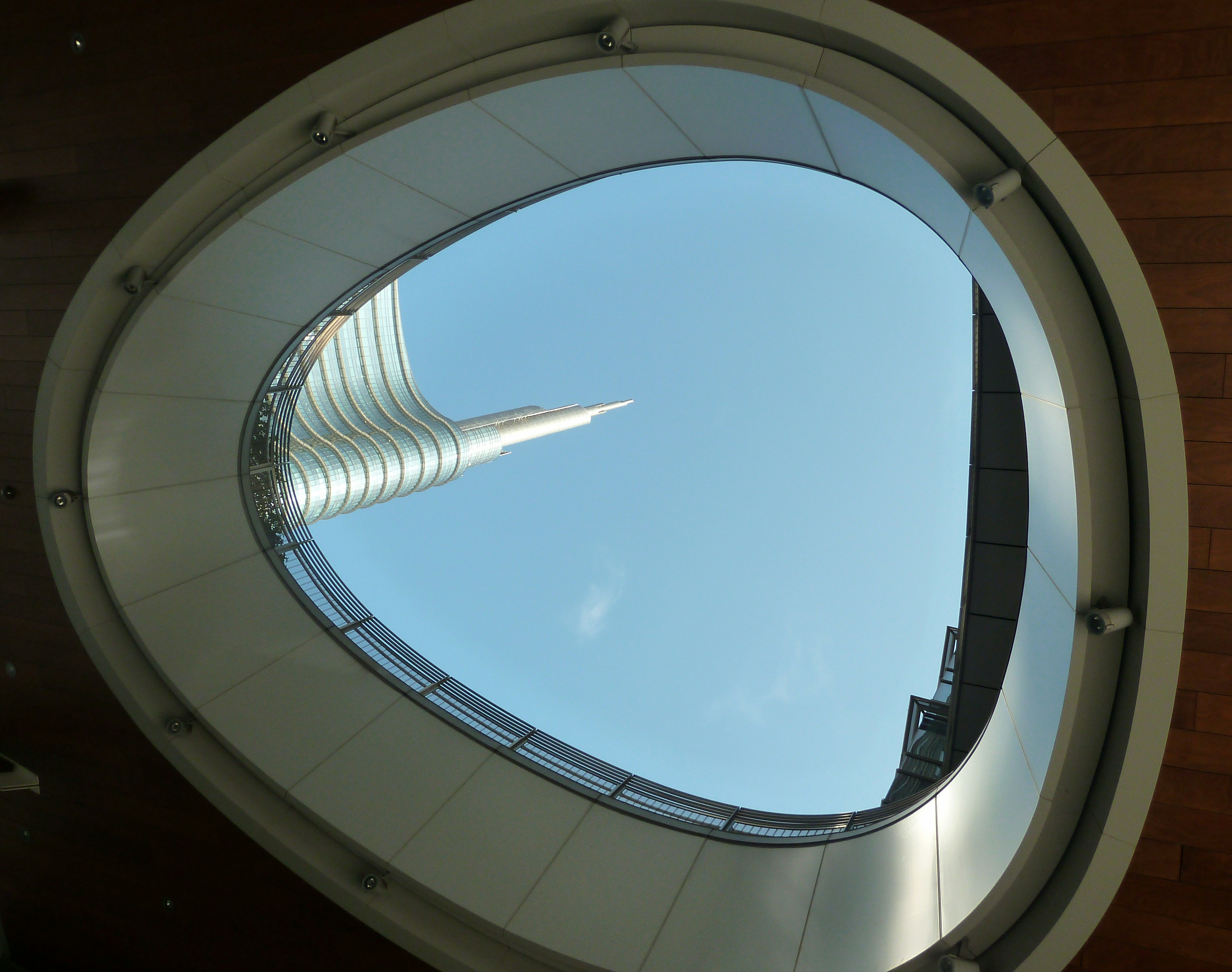 a view of a building through a circular window, A hole to the sky