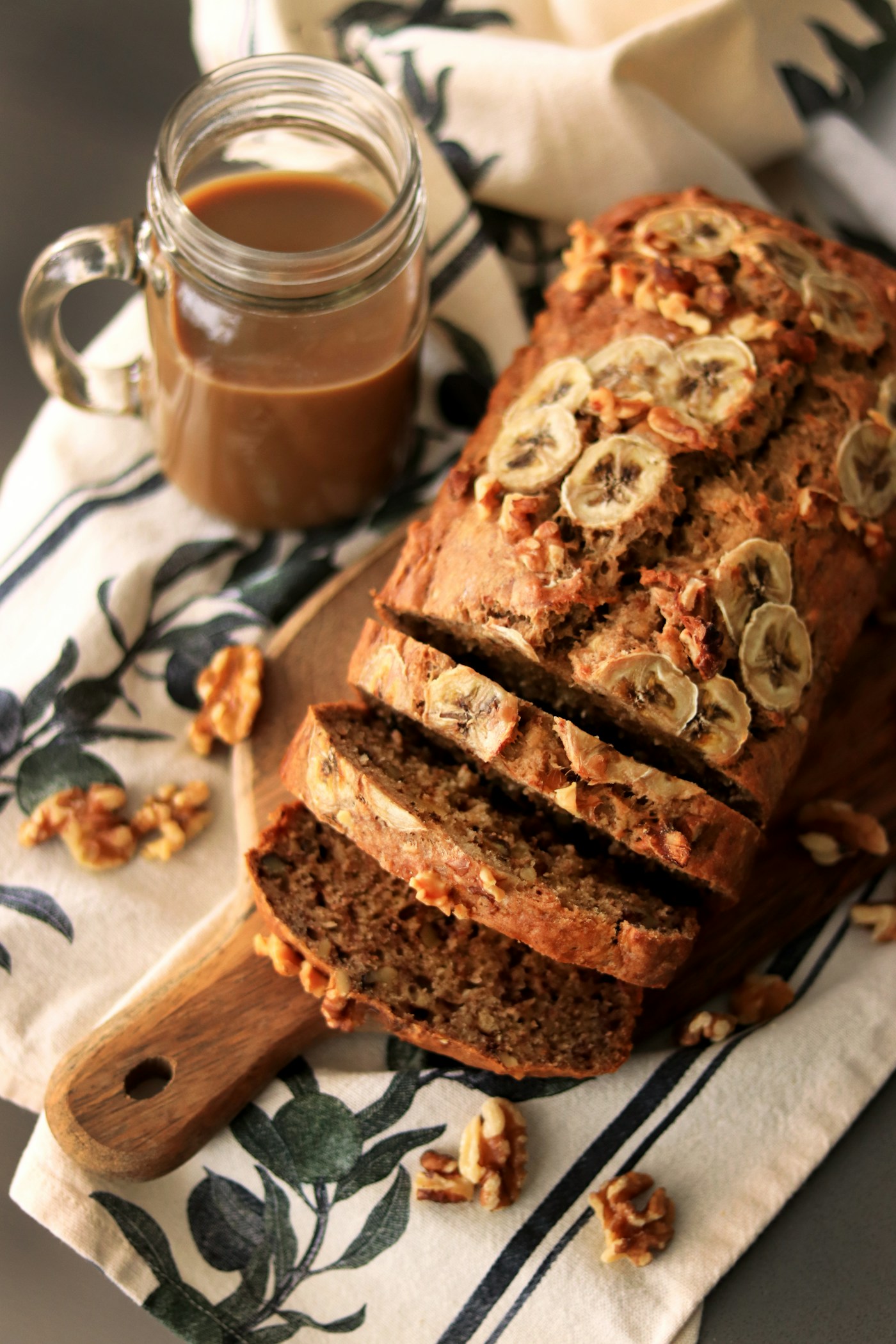 Sliced moist banana bread loaf with golden crust on a wooden board