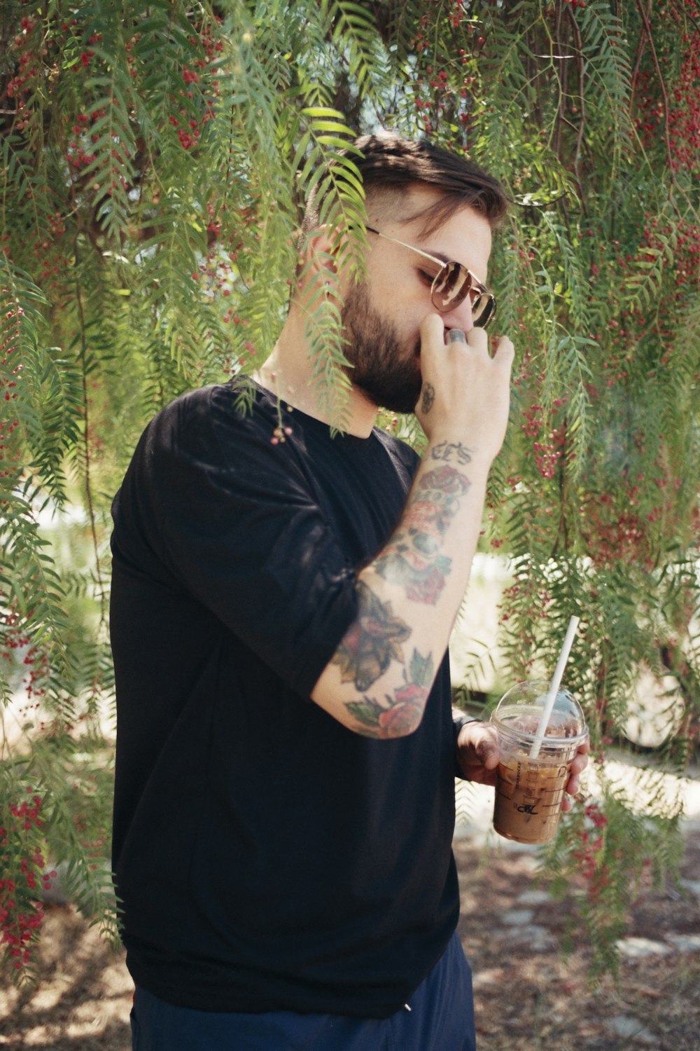 a man standing under a tree talking on a cell phone