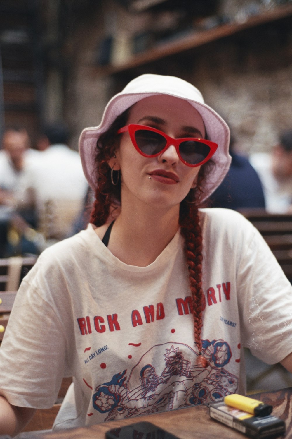 a woman sitting at a table wearing a pink hat and sunglasses