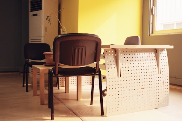 A modern metal-frame folding table set up for a small home office with natural light.