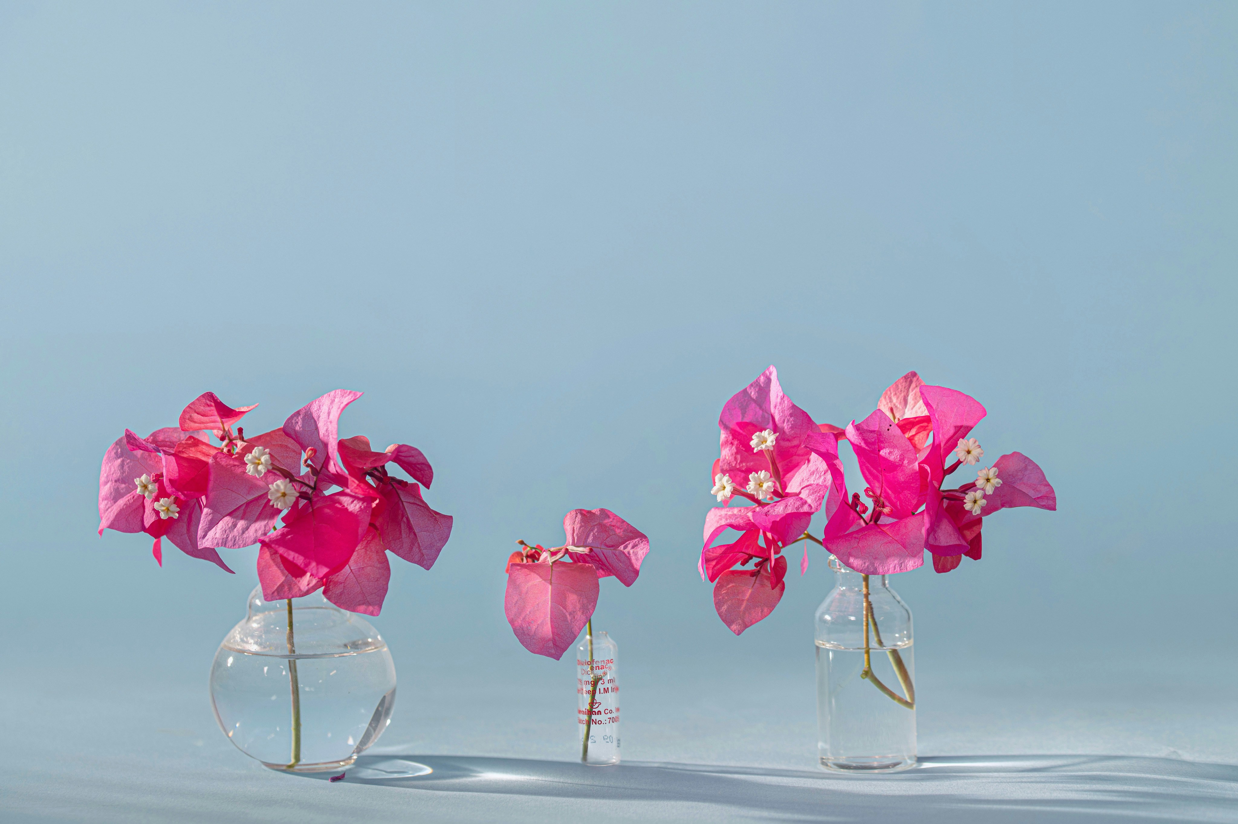 three clear vases with pink flowers in them