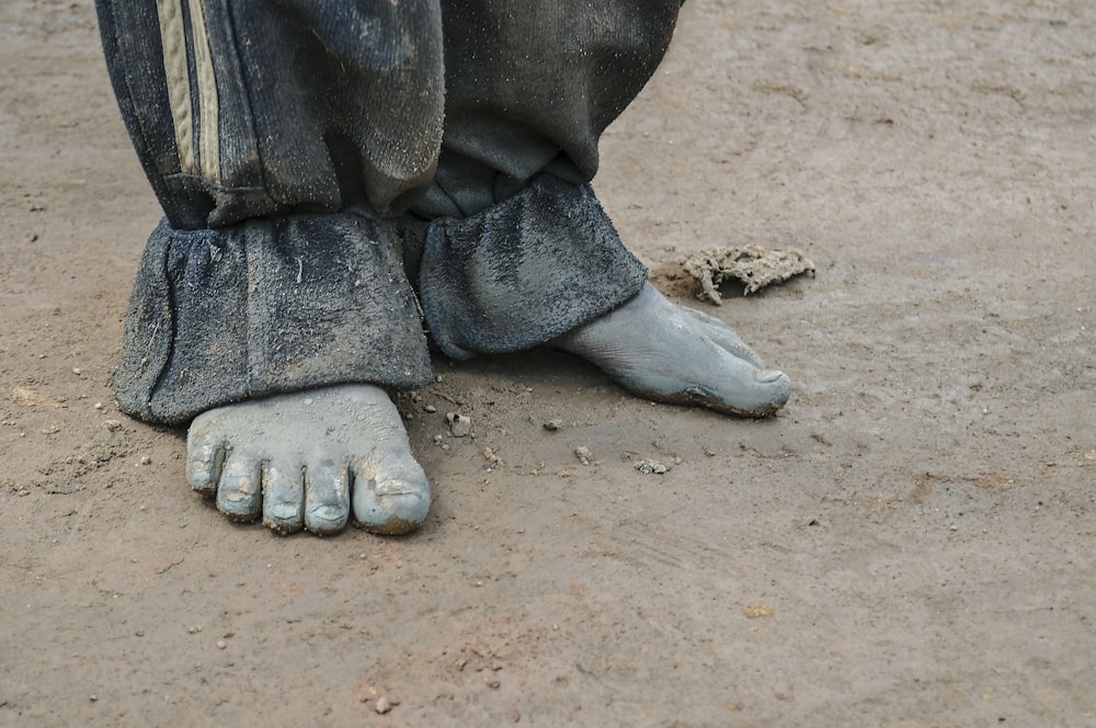 a close up of a person's feet with dirt on the ground