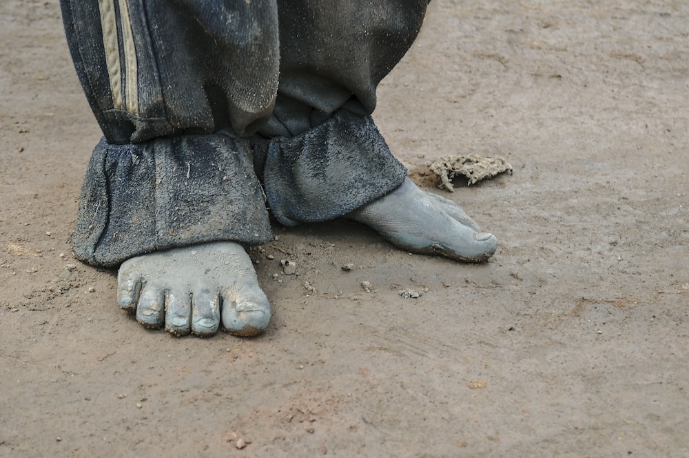 un gros plan des pieds d’une personne avec de la saleté sur le sol