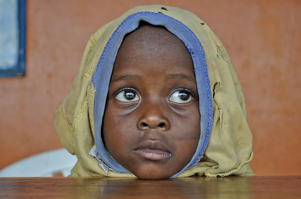 a young child wearing a yellow and blue head covering