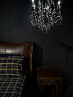 A softly lit bedroom showcasing a tufted velvet headboard in deep plum with gold bedside sconces.