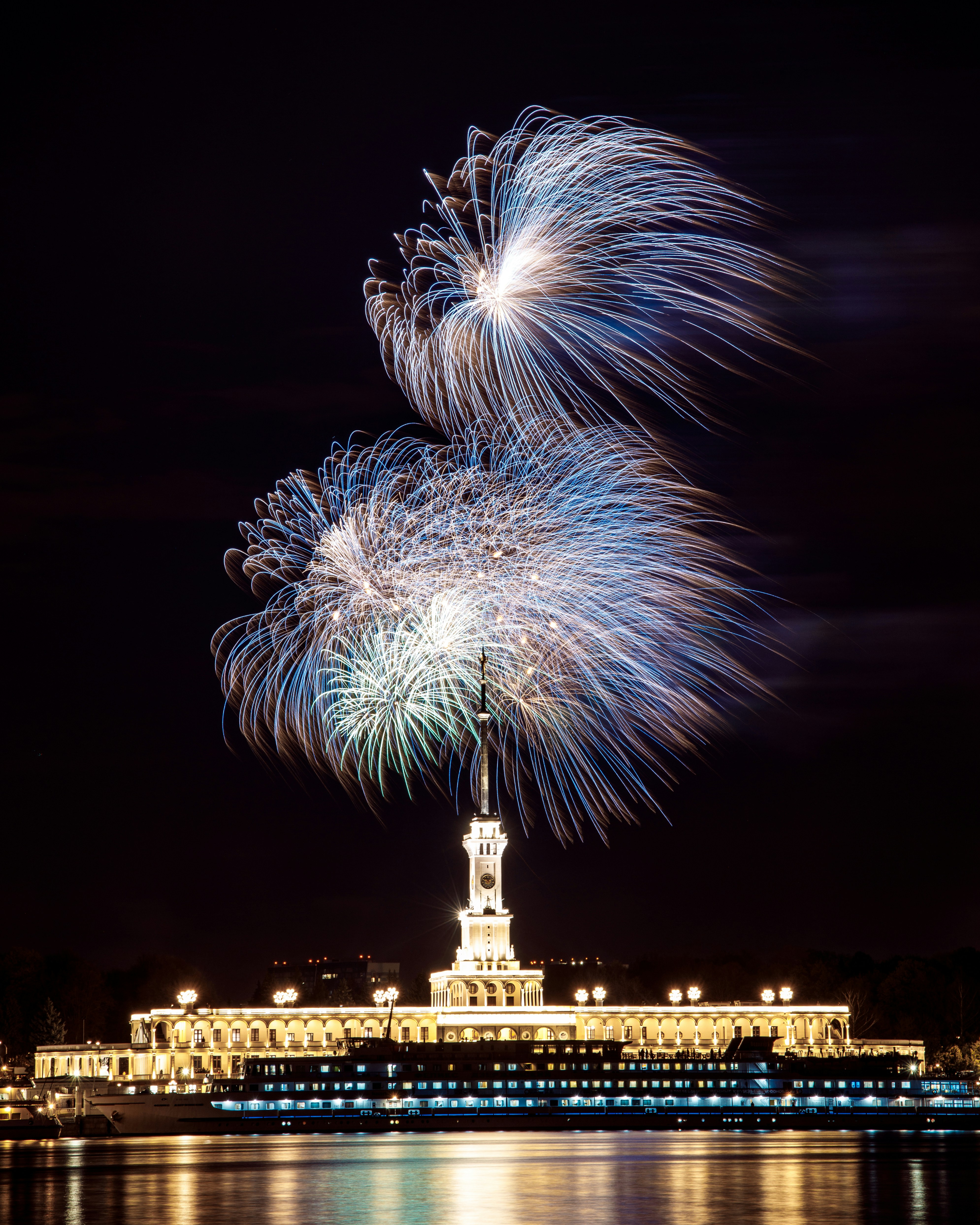 fireworks are lit up in the night sky over a large building