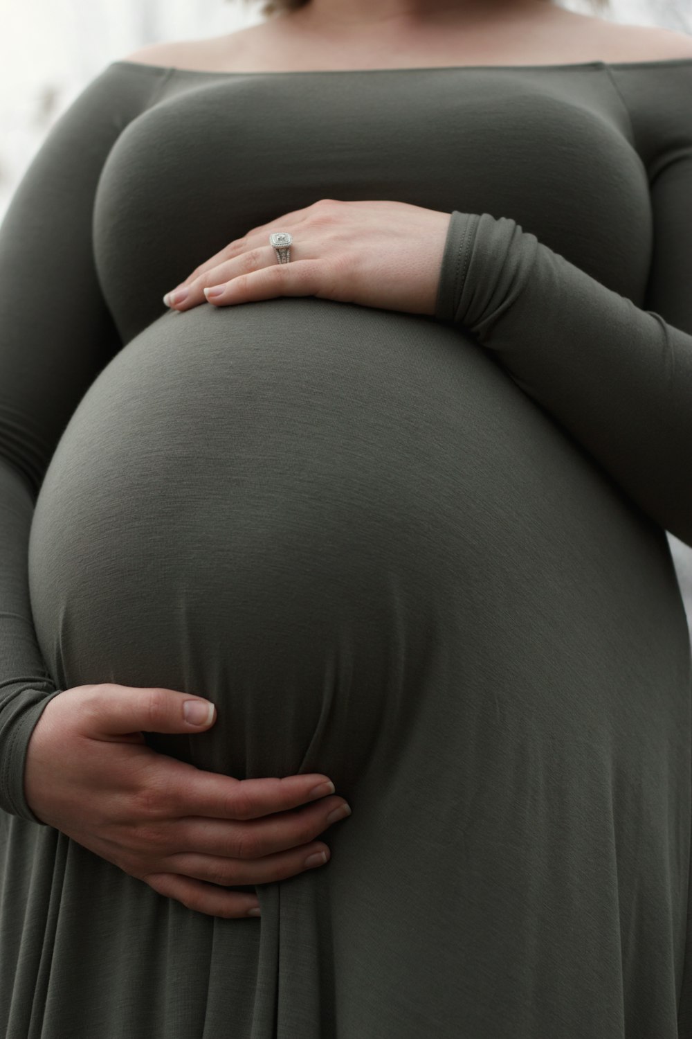 a pregnant woman in a green dress holding her belly