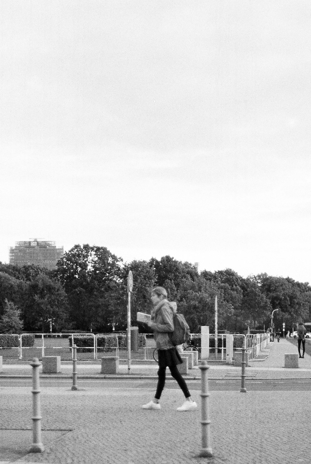 a woman walking down a street next to a park