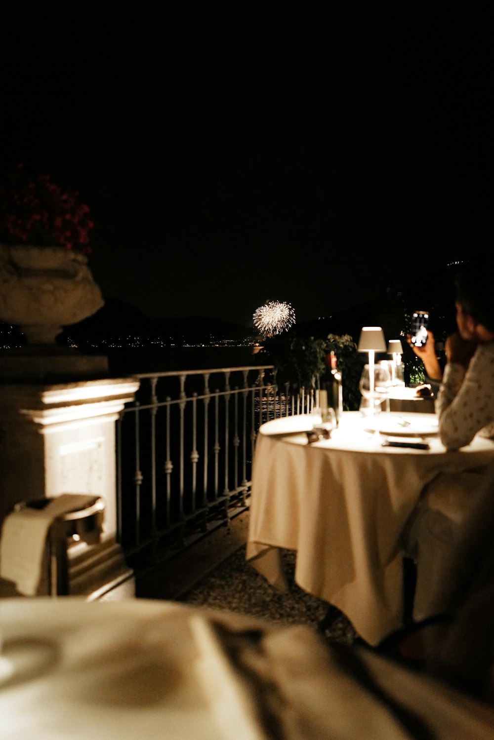 a person sitting at a table on a balcony at night