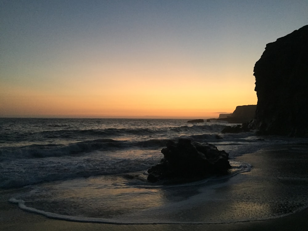 the sun is setting over the water at the beach