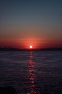 A vibrant sunset reflecting on a calm ocean surface.