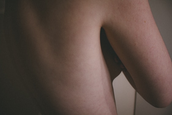 A close-up image of a human body focusing on a section of the back and side arm. The skin is pale with subtle shadows emphasizing the contours.