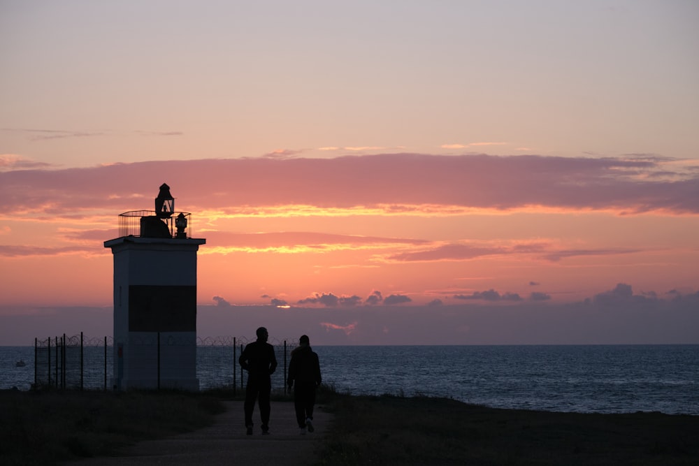 a couple of people that are standing in front of a lighthouse