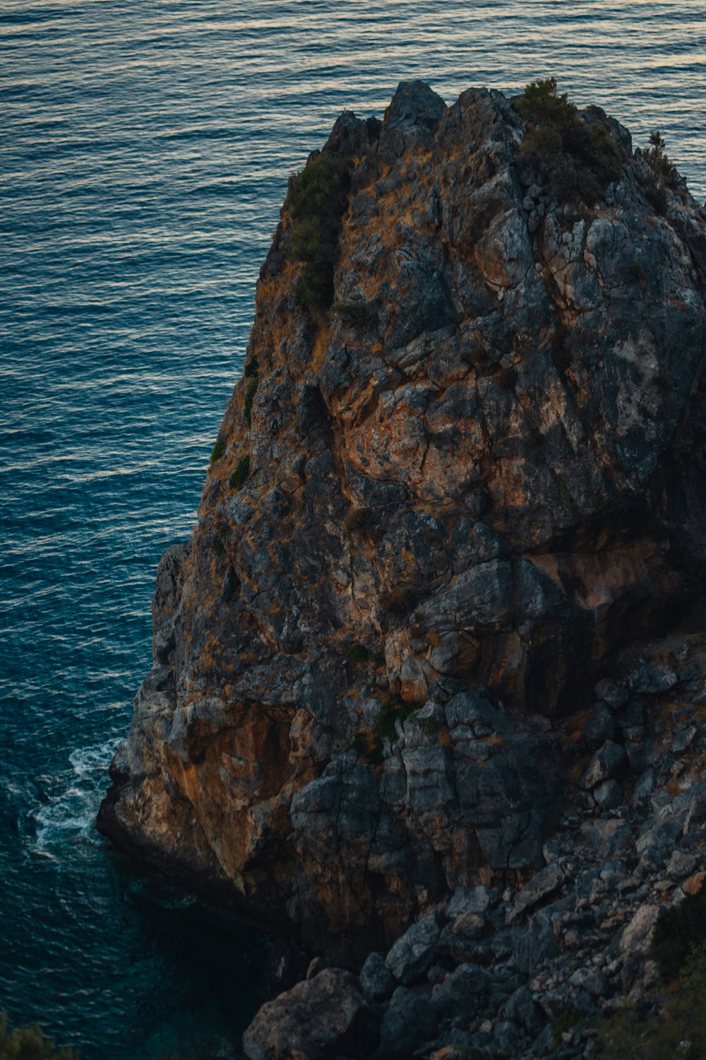 Eine Person, die auf einem großen Felsen neben dem Meer steht