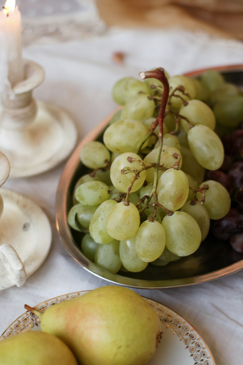 a plate of grapes and pears on a table