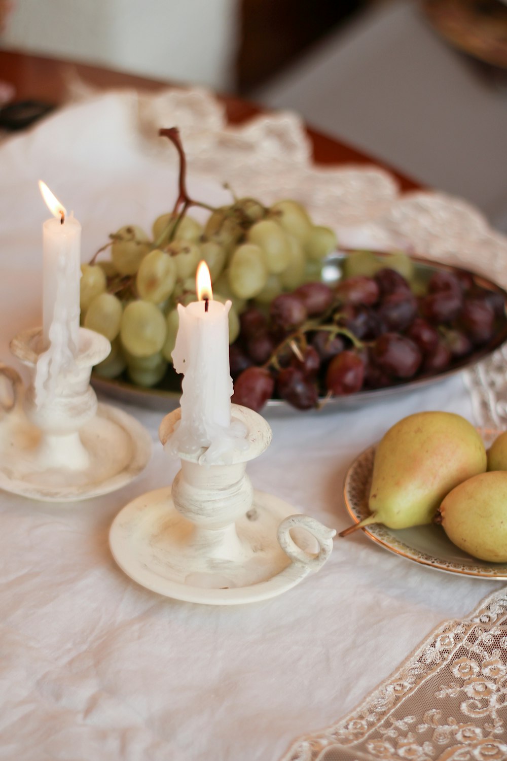 a table topped with plates of fruit and candles