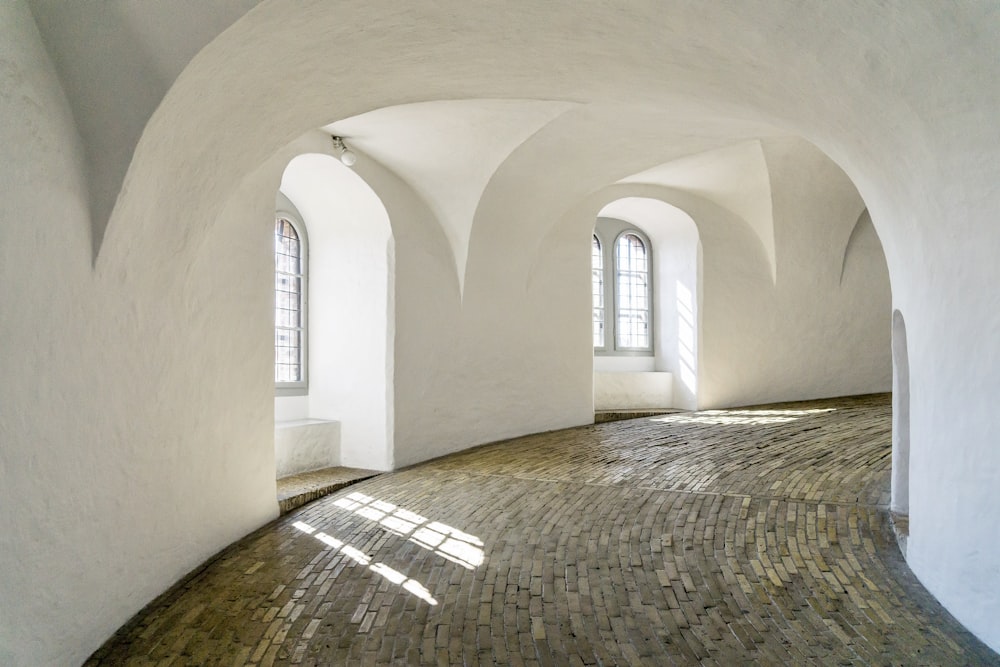 a room with a brick floor and arched windows