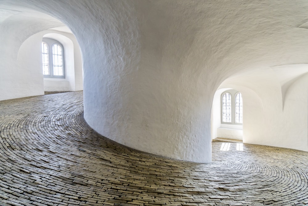 a circular room with a stone floor and arched windows