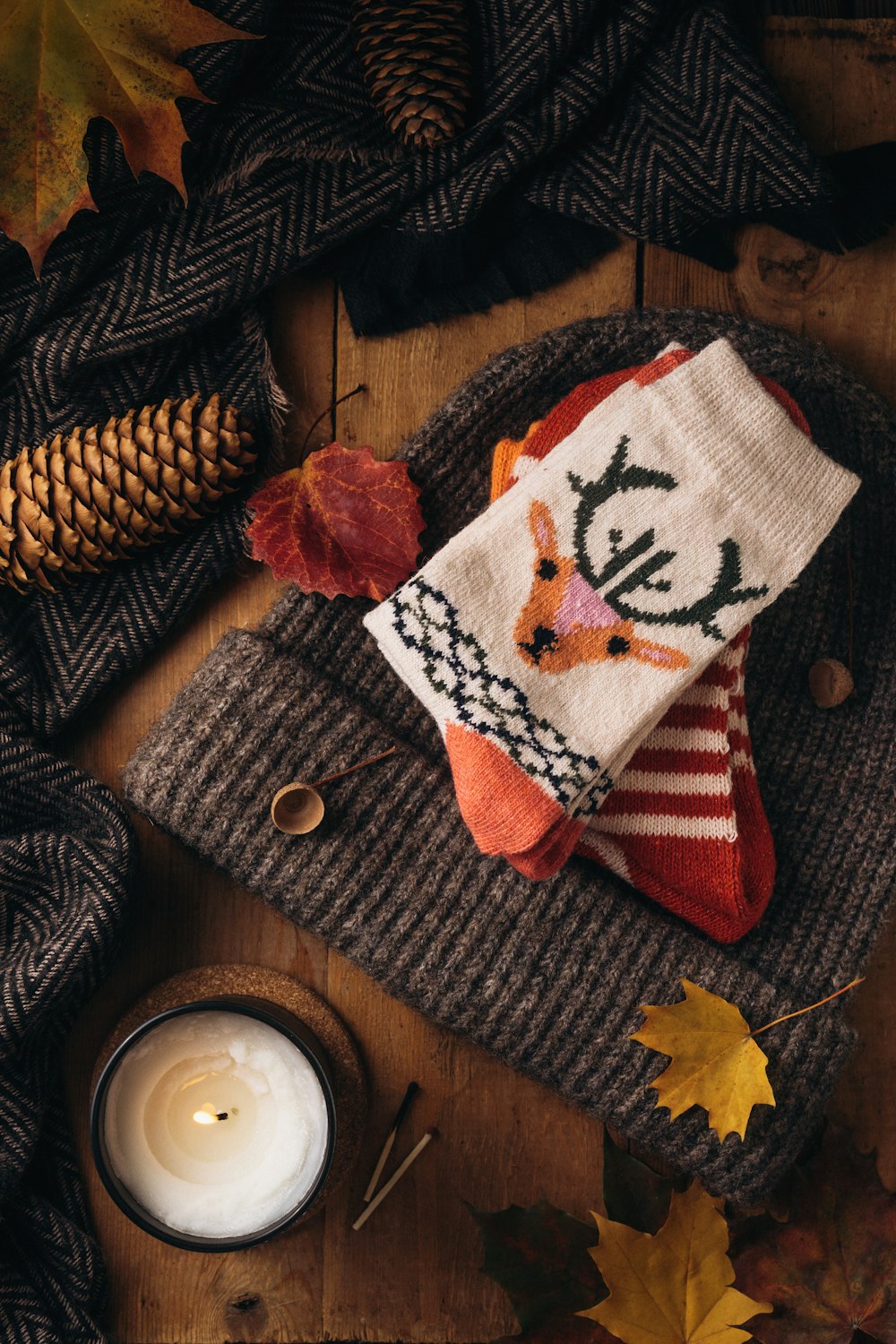 a knitted scarf with a deer on it next to a candle