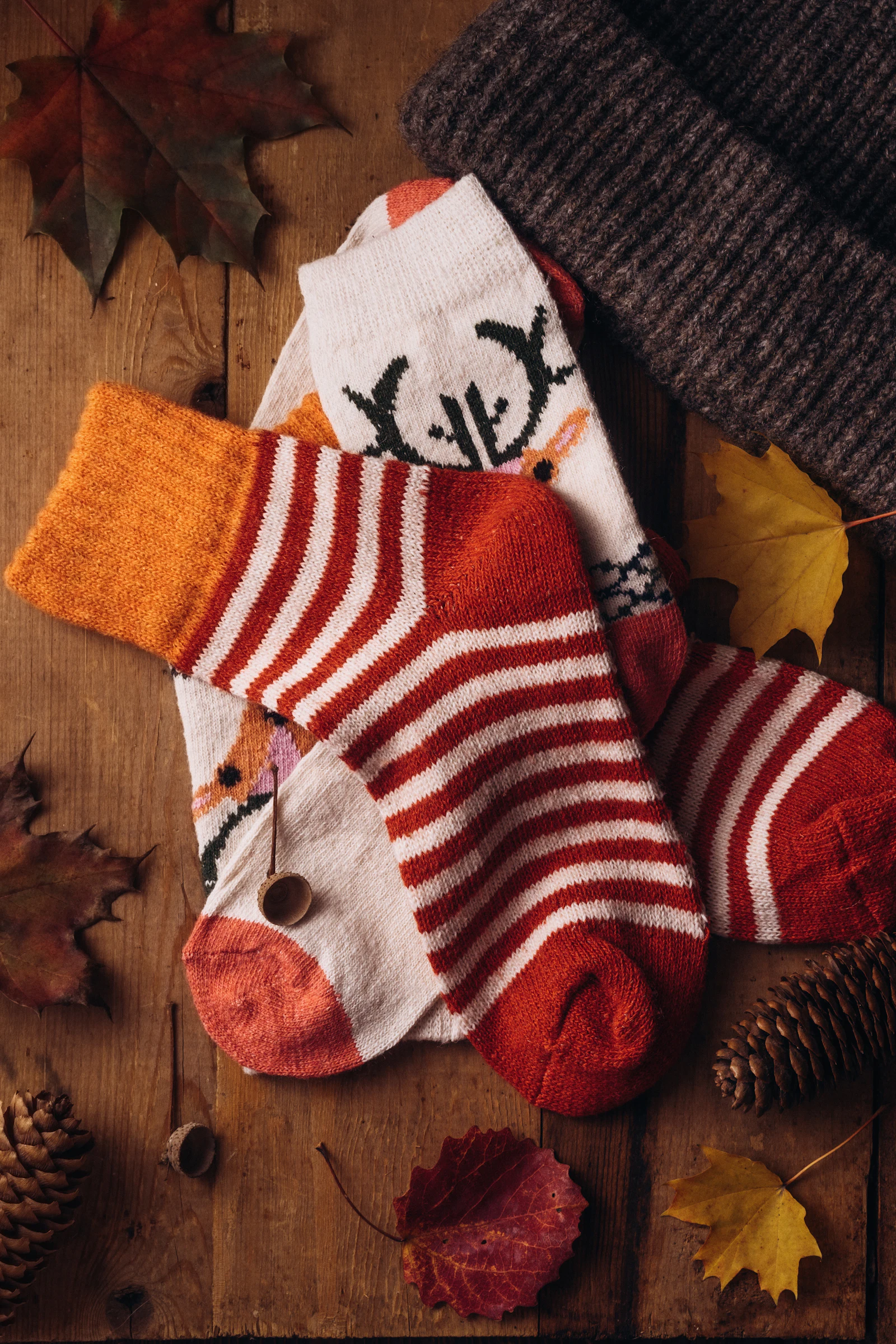 Knitted socks and a hat on a wooden table