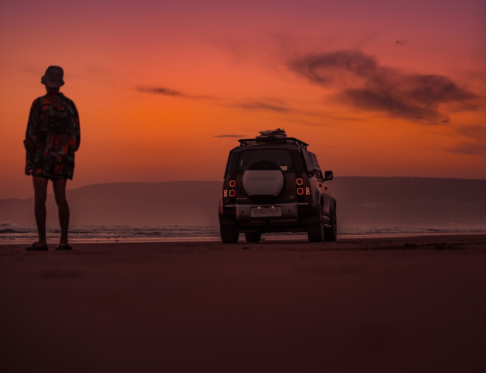 a man standing next to a vehicle on a beach