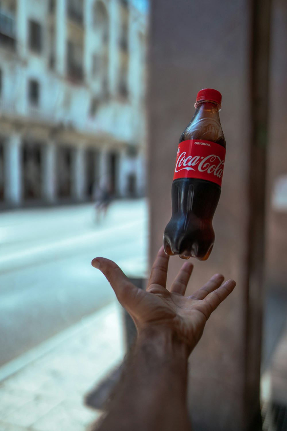 a hand holding a bottle of coca cola