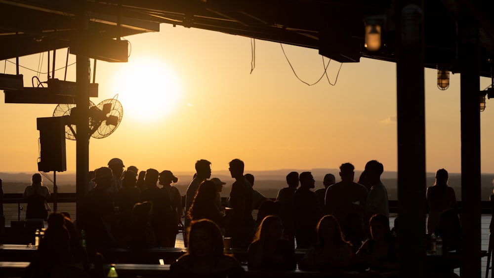 a crowd of people standing around a building at sunset